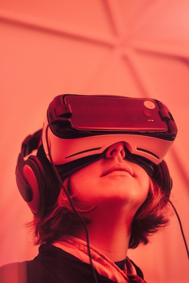 Person wearing a VR headset and headphones under red lighting, looking upward