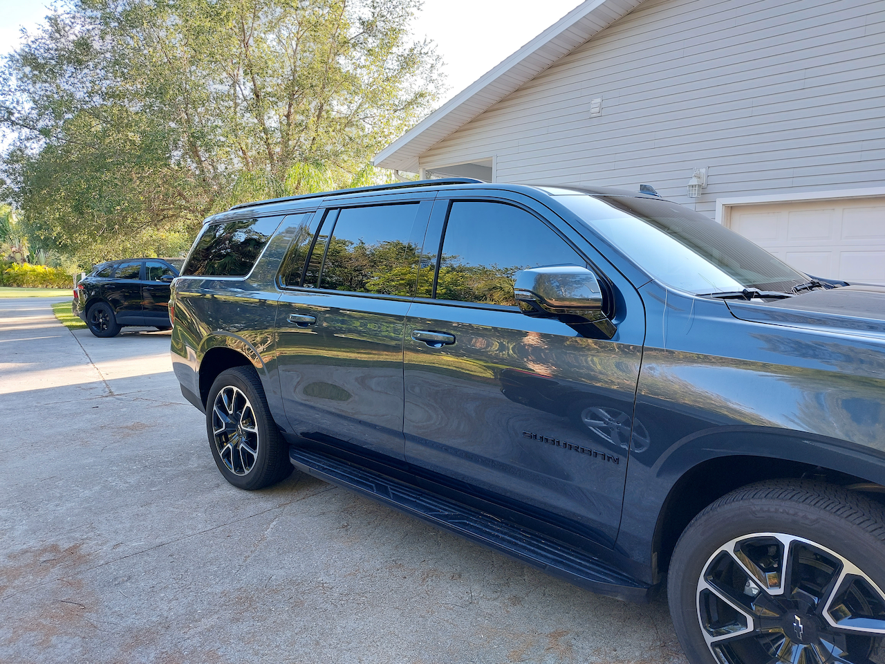 A black suv is parked in front of a house.