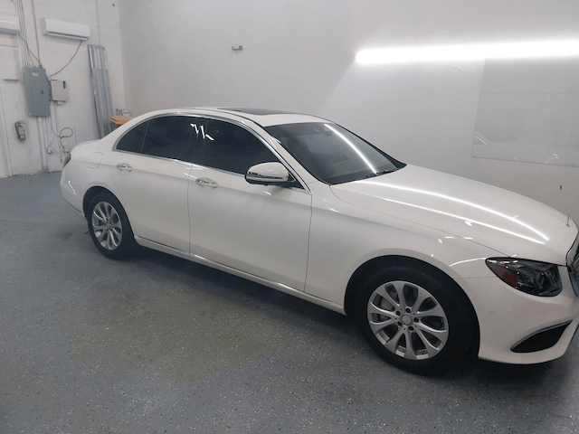 A white mercedes benz is parked in a garage.