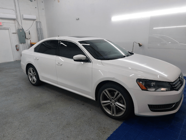 A white volkswagen passat is parked in a garage