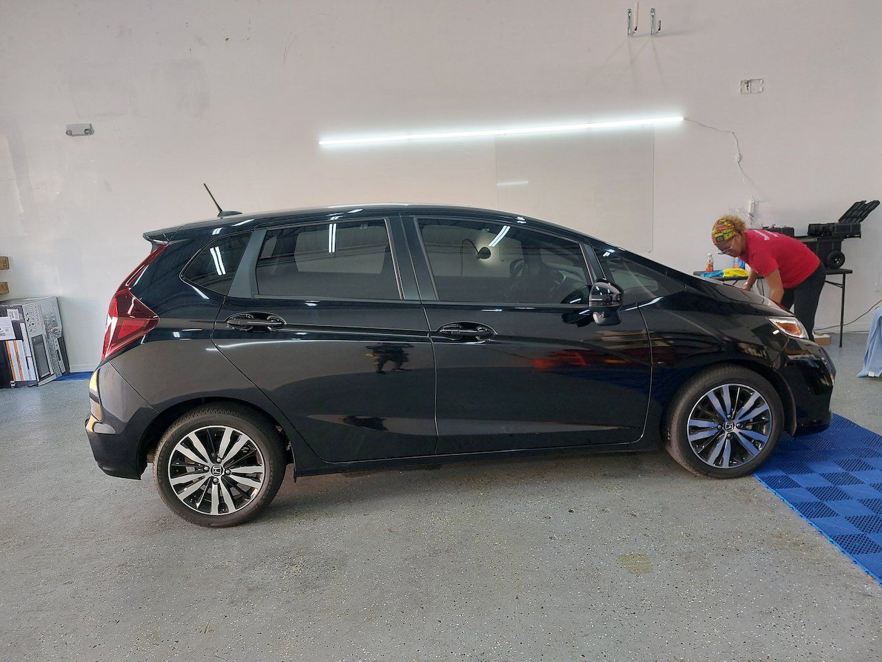 A black honda jazz is parked in a garage.
