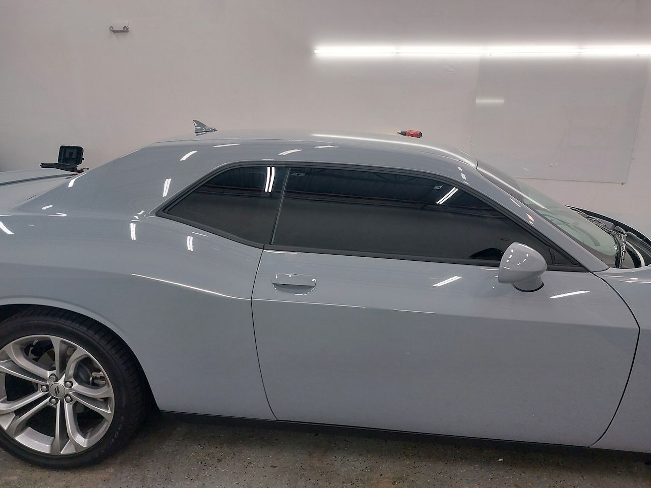 A white dodge challenger is parked in a garage.