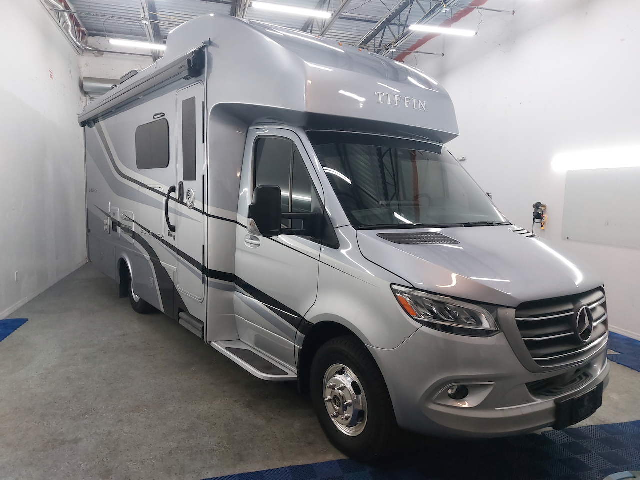 A silver rv is parked in a garage.