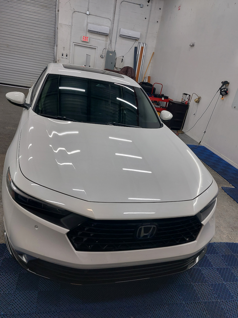 A white honda accord is parked in a garage.