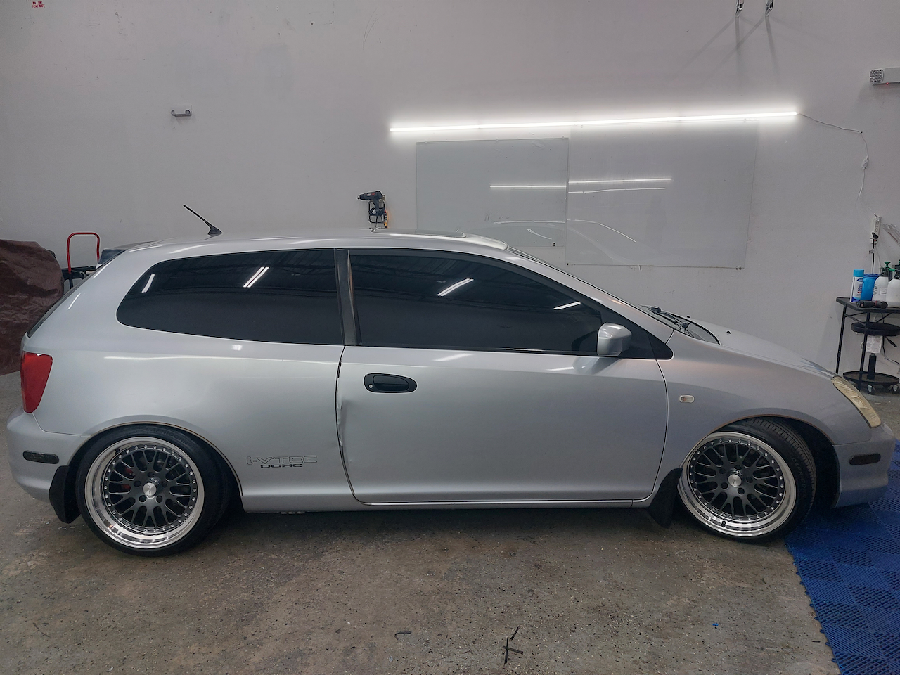 A silver hatchback car is parked in a garage.