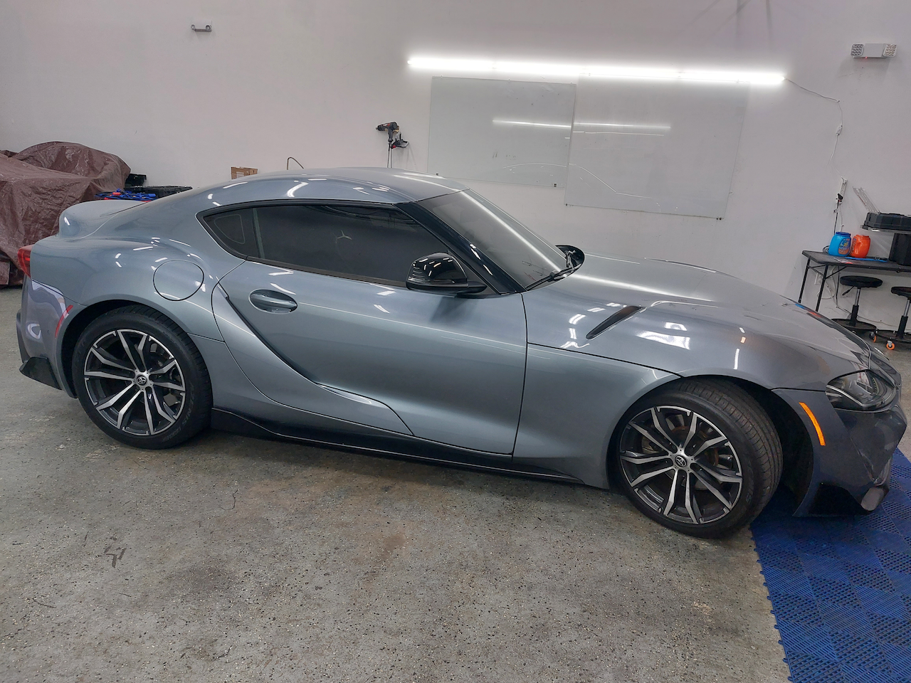 A gray toyota supra is parked in a garage.
