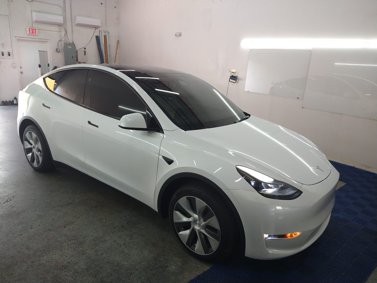 A white tesla model y is parked in a garage.