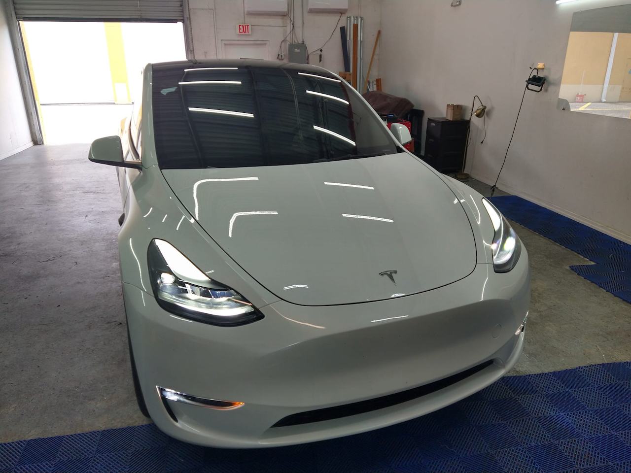 A white tesla model 3 is parked in a garage.