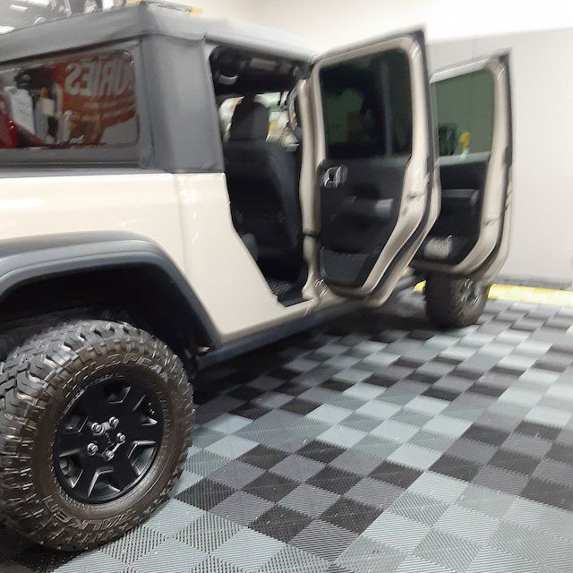 A jeep is parked in a garage with its doors open