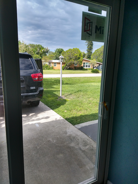 A car is parked in front of a sliding glass door.