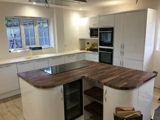 A kitchen with white cabinets and a wooden counter top.