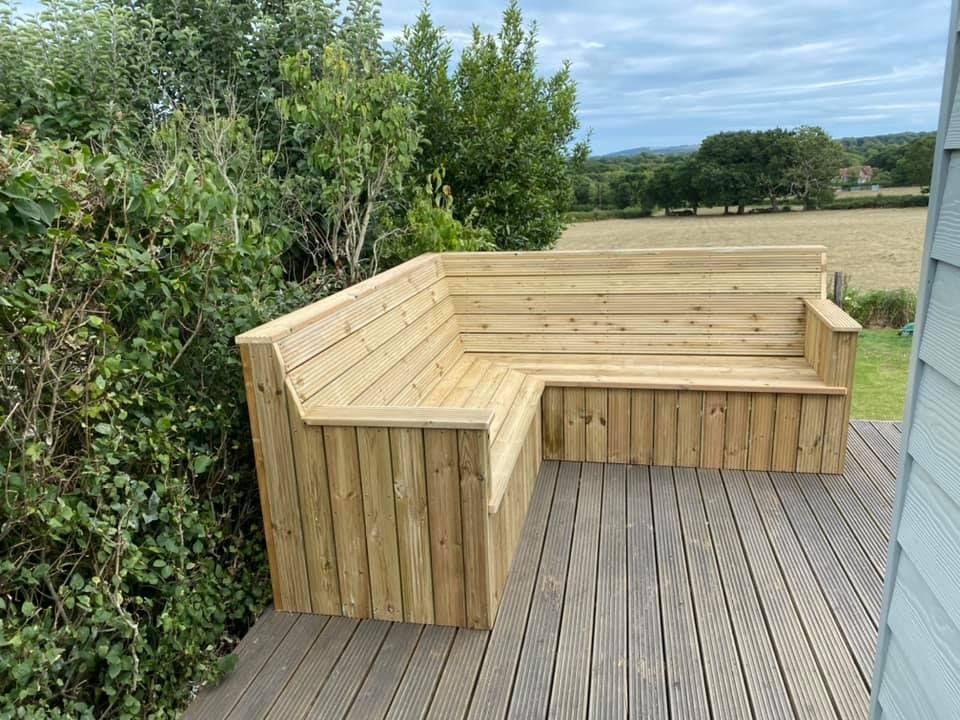 A wooden bench is sitting on top of a wooden deck.