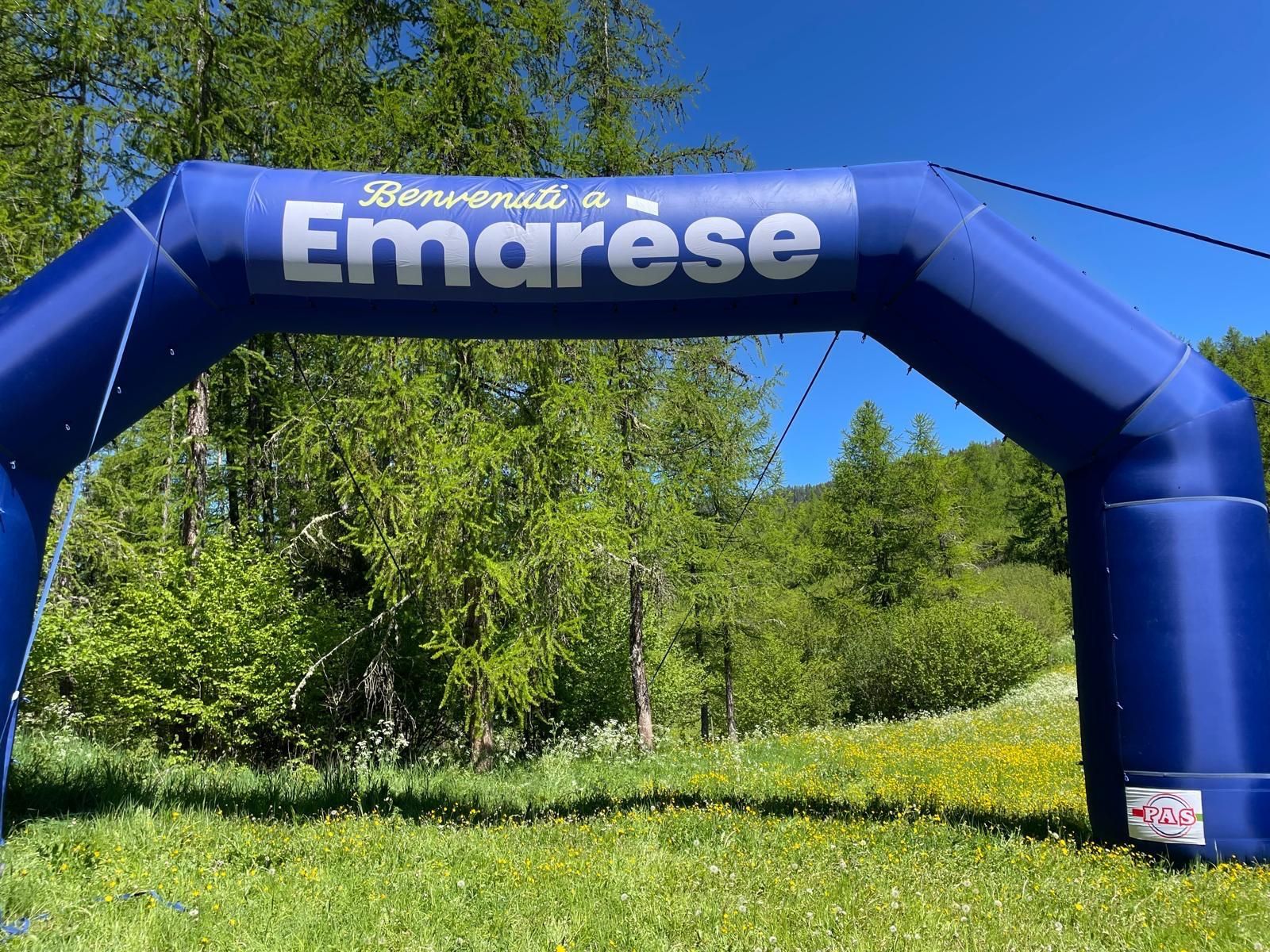 Arco gonfiabile blu in stile Emarsé sopra un sentiero erboso in un parco verde e soleggiato.