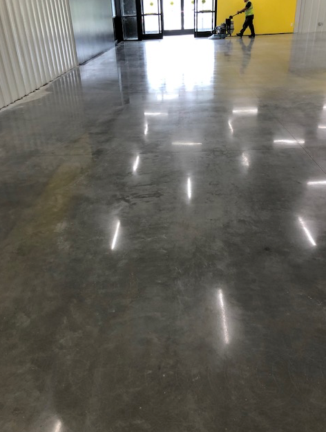 A person is walking on a shiny concrete floor in a building.