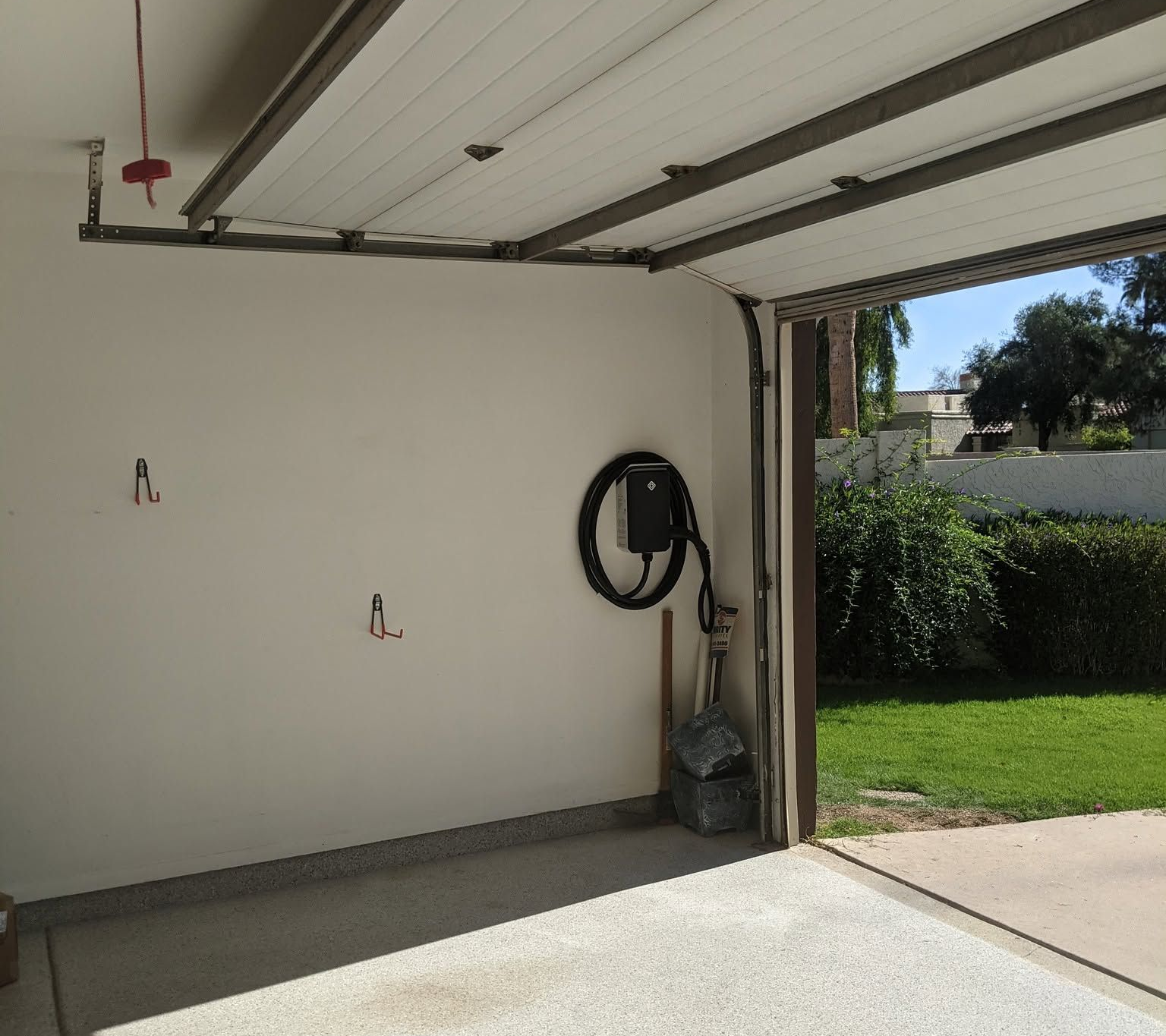 Empty garage interior with open door to sunny driveway and green lawn outside