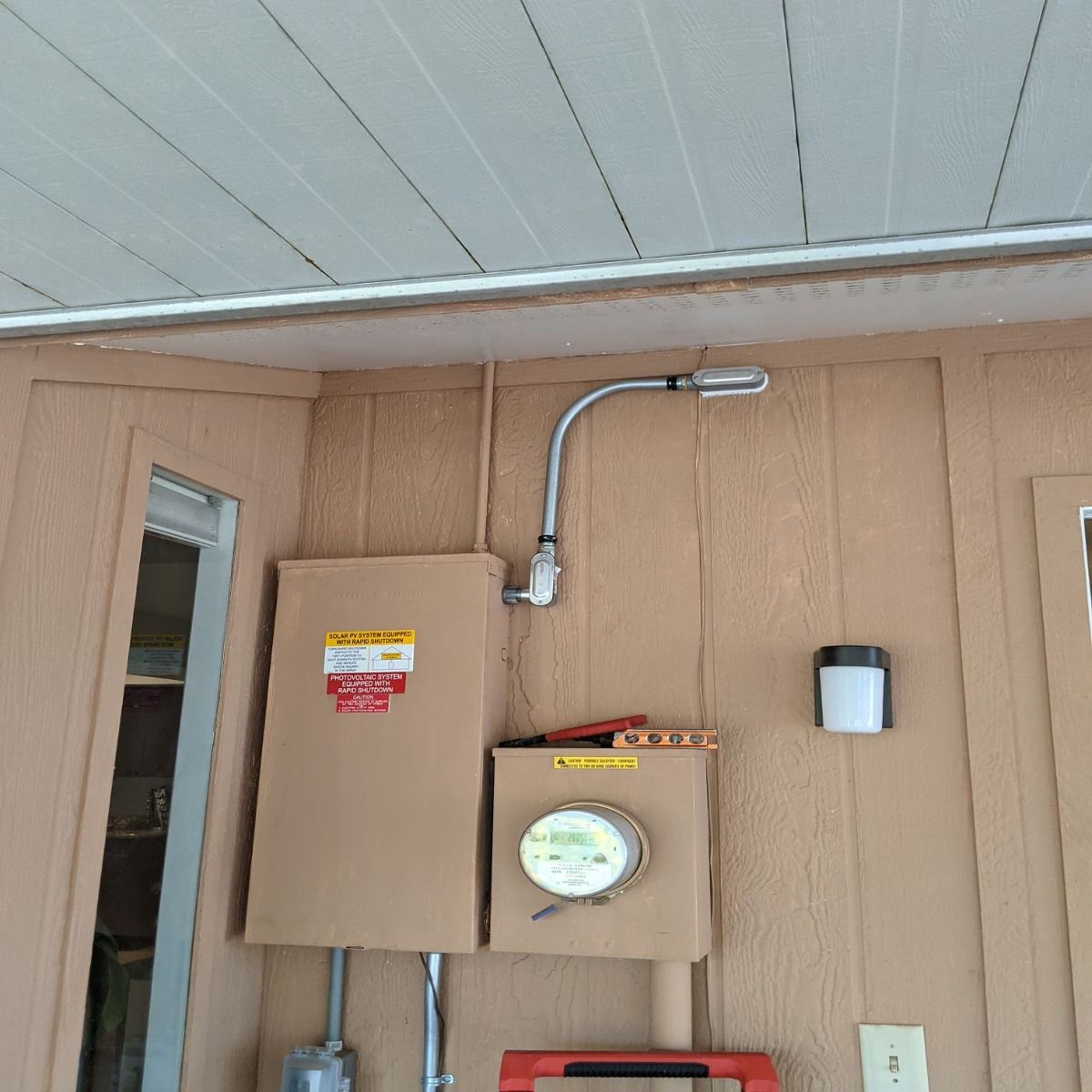 Indoor utility wall with electrical panels, conduit, and a small round meter under a white ceiling