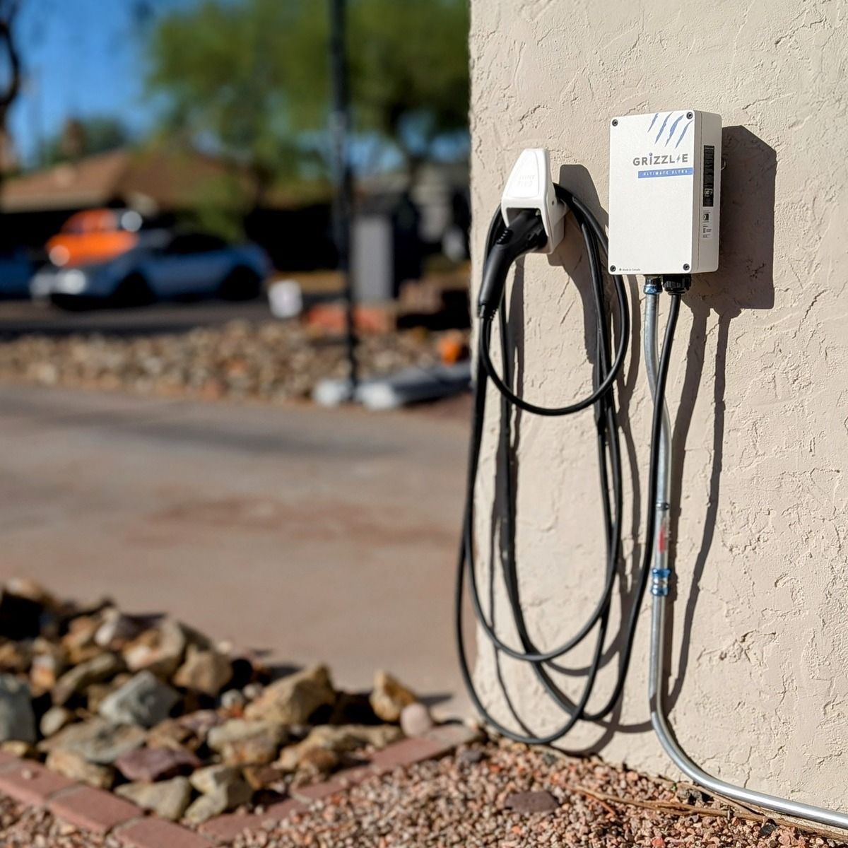 EV charging station mounted on a wall with plugged-in cables near a parking lot