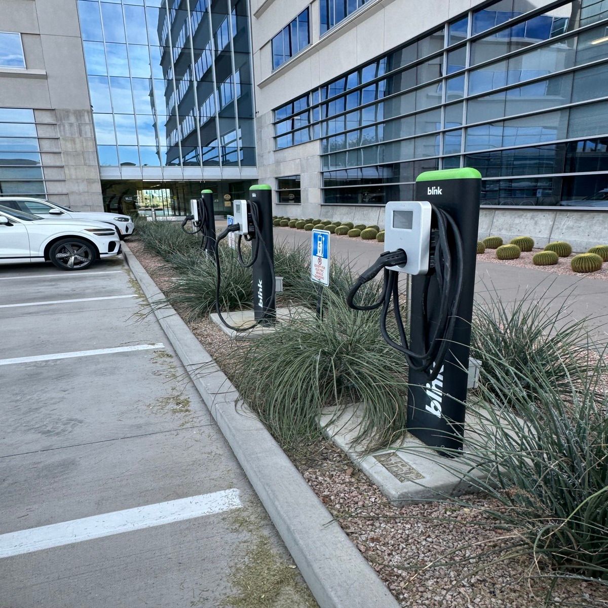 EV charging stations in a parking lot beside a modern glass office building
