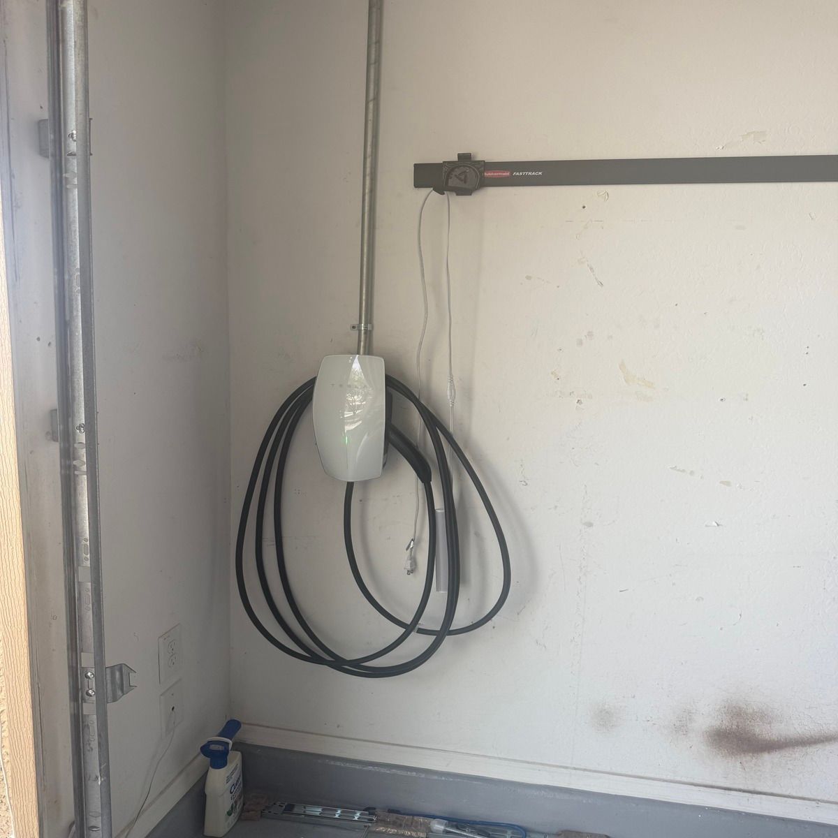 Wall-mounted electrical box with coiled black cables in a plain utility room.