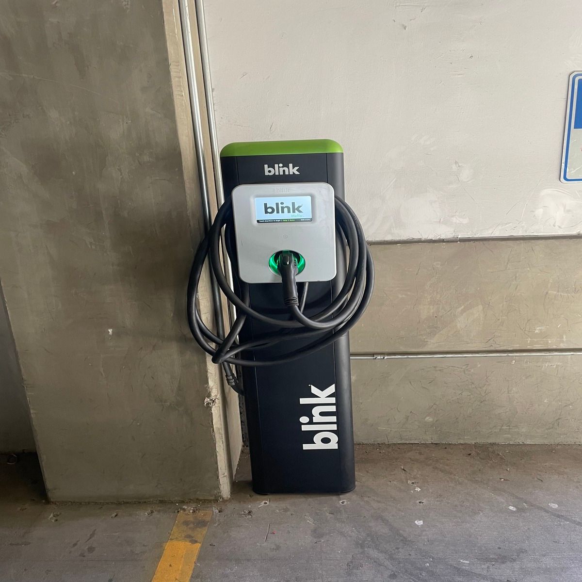 Blink EV charging station with a coiled cable against a wall indoors