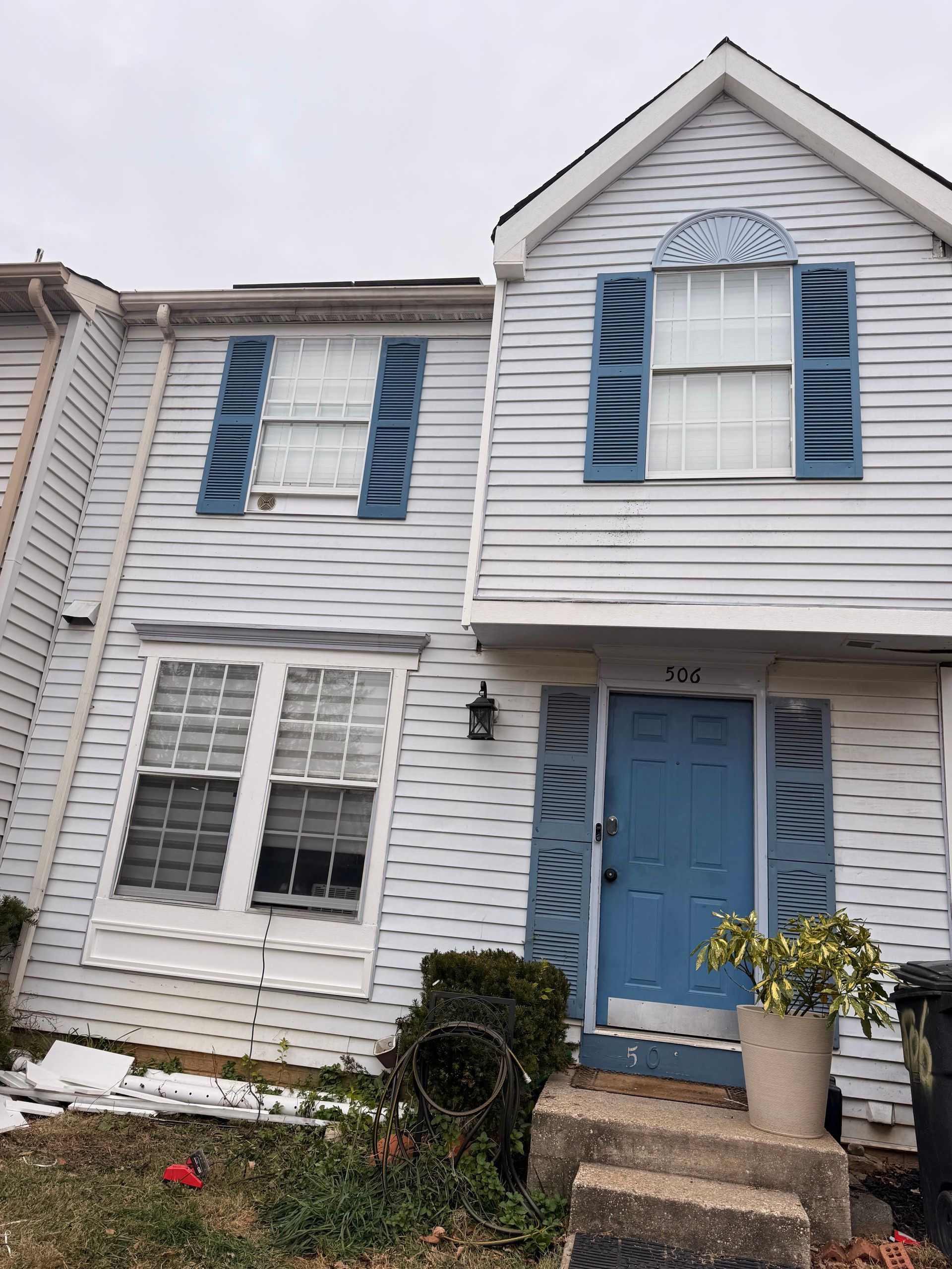 Blue-and-white townhouse with shutters, front door, and small front garden.
