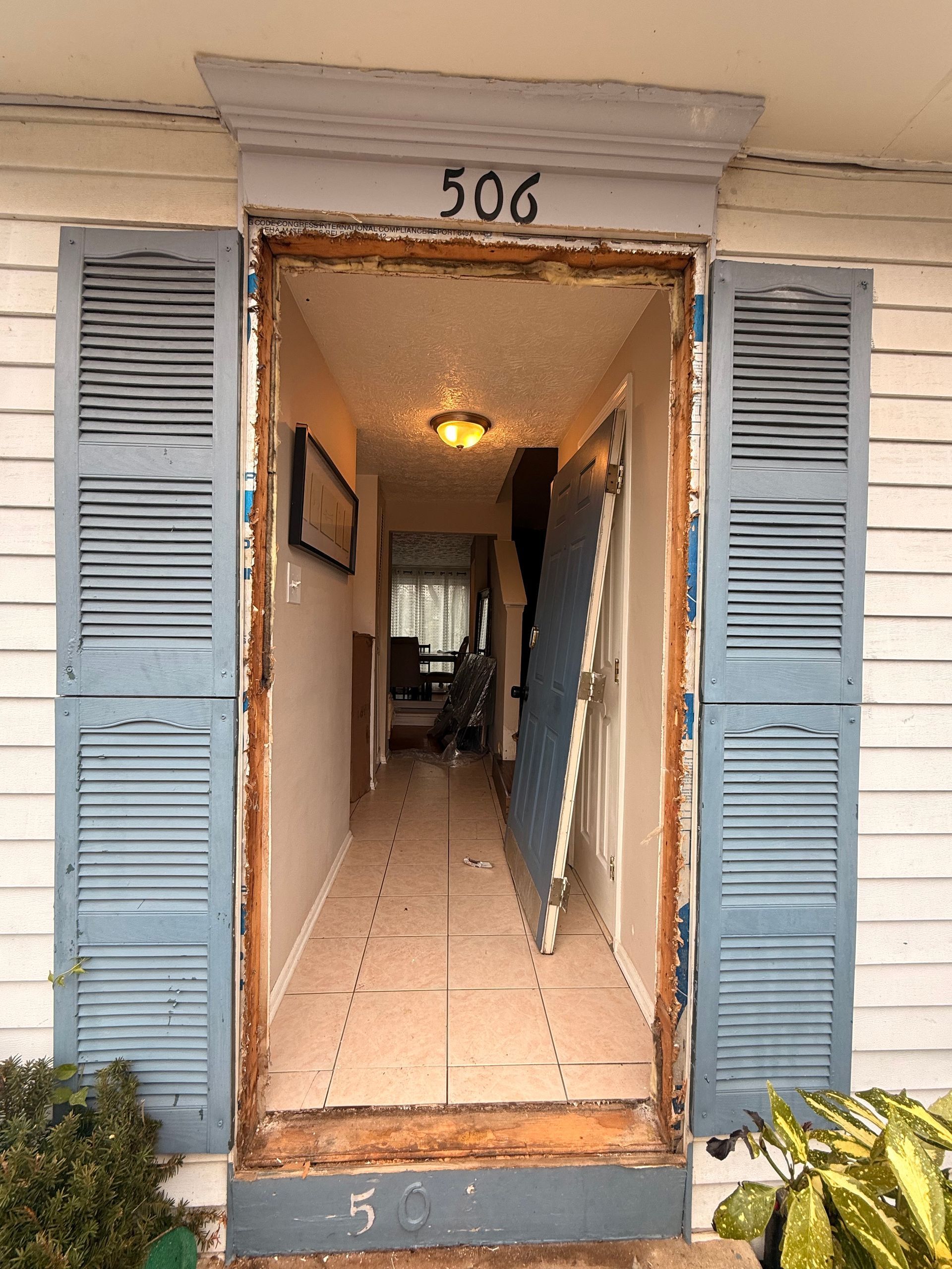Open apartment doorway numbered 506 with blue shutters and a lit hallway beyond.