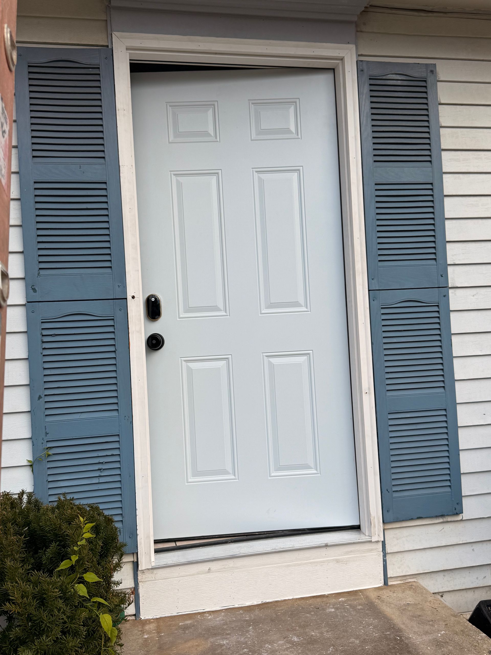 White front door with blue shutters on a house exterior