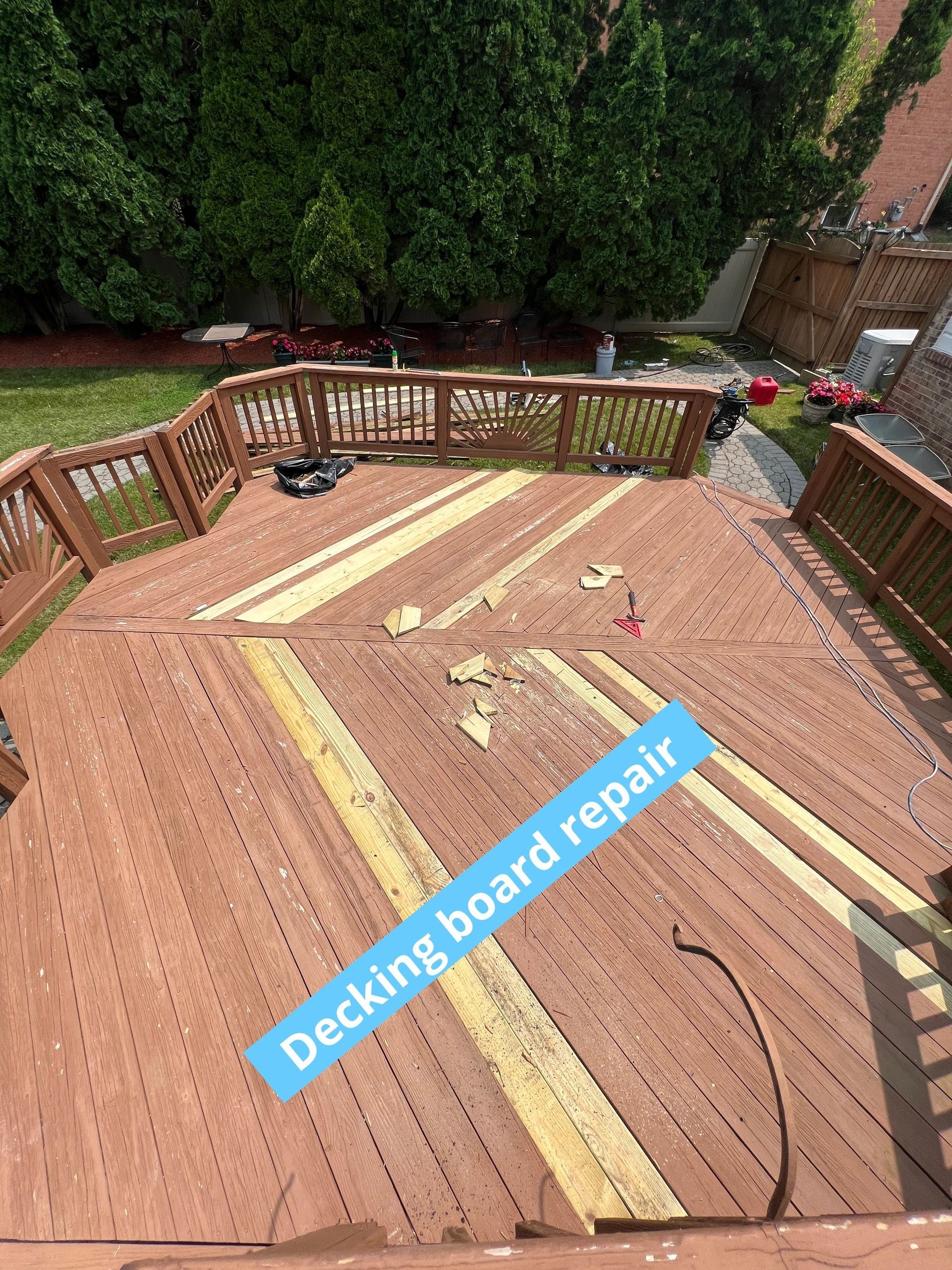 Decking board repair on a wooden backyard deck with exposed boards and railings.