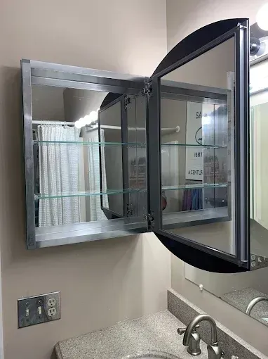 Bathroom vanity with open mirrored medicine cabinet above the sink and faucet