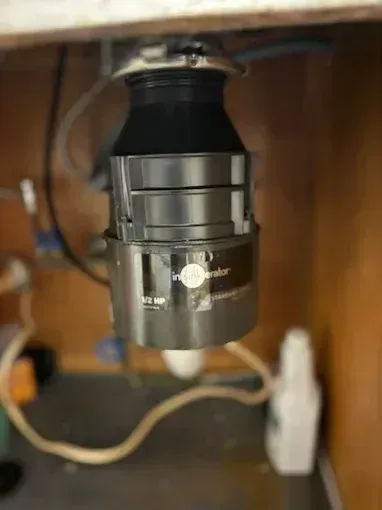 Black camera lens mounted under a shelf in a wooden cabinet