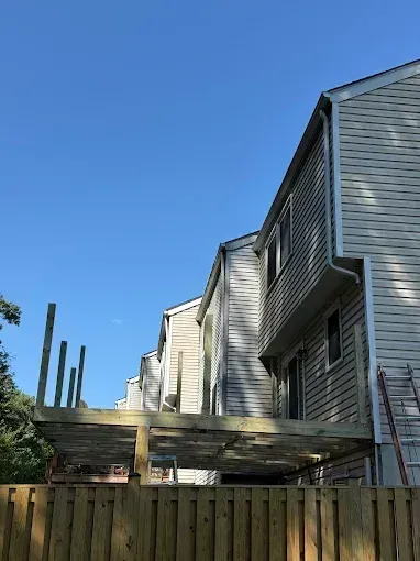 Row of gray townhouses with a wooden fence and blue sky above