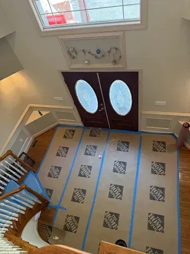 Front entry foyer with double oval-glass doors, tiled floor, and staircase railing.
