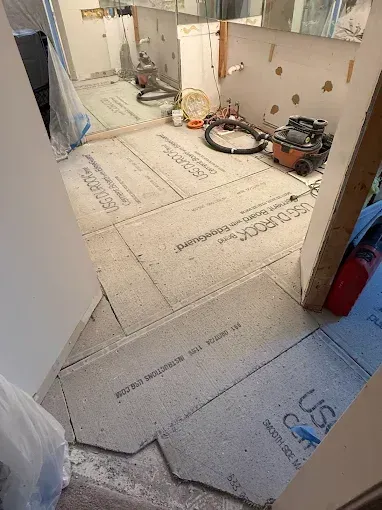 Renovation room with floor underlayment panels laid out and tools along the wall