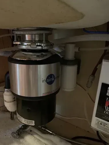 Under-sink InSinkErator garbage disposal unit mounted beneath a kitchen sink