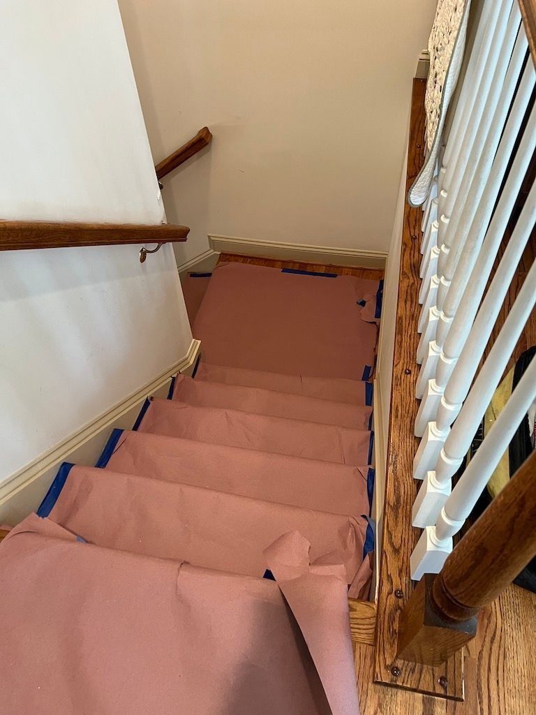 Carpeted staircase with wooden handrails and white balusters, viewed from the top looking down.