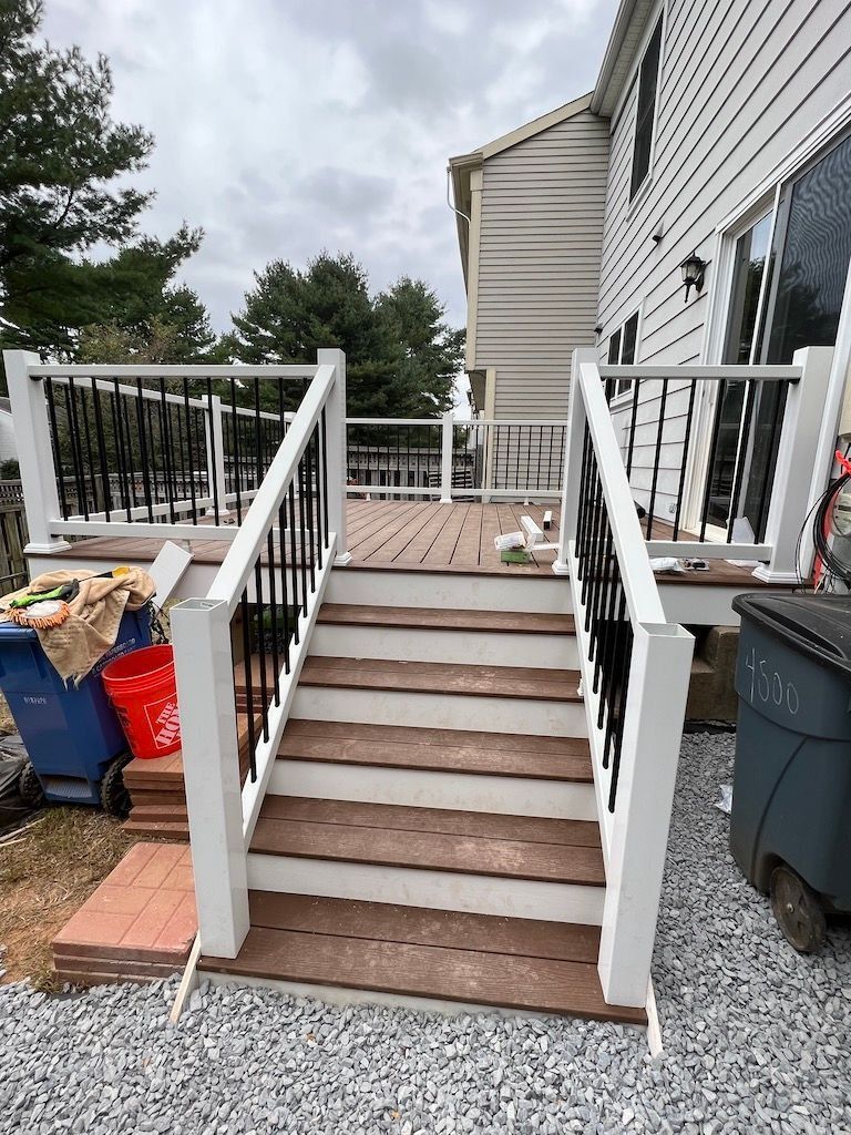 Backyard steps with white railings leading to a deck beside a house