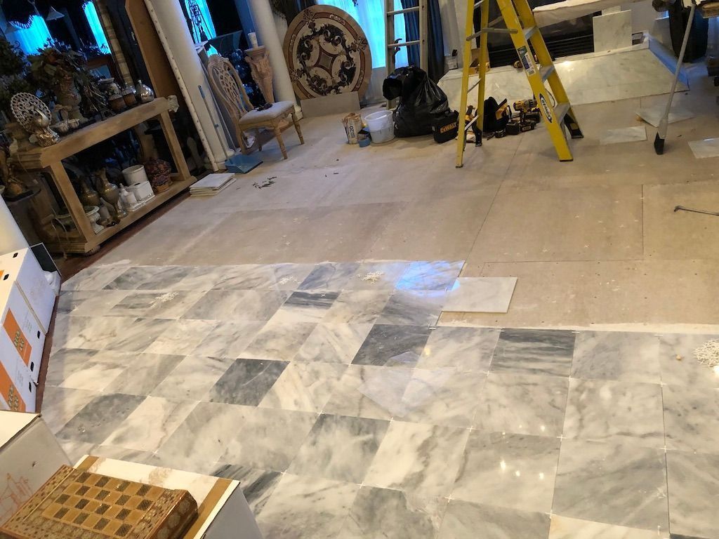 Interior under renovation with tiled floor, ladders, tools, and construction materials scattered around.