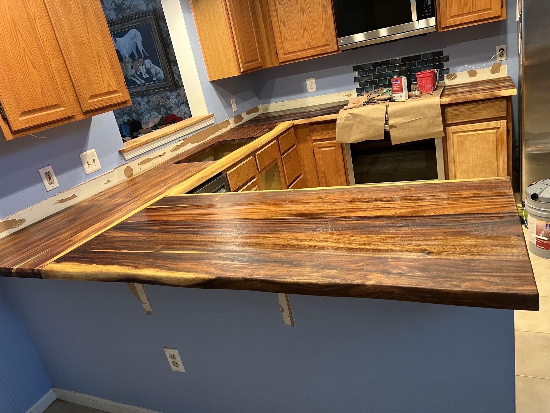 Partially remodeled kitchen with a dark wood island countertop and wooden cabinets