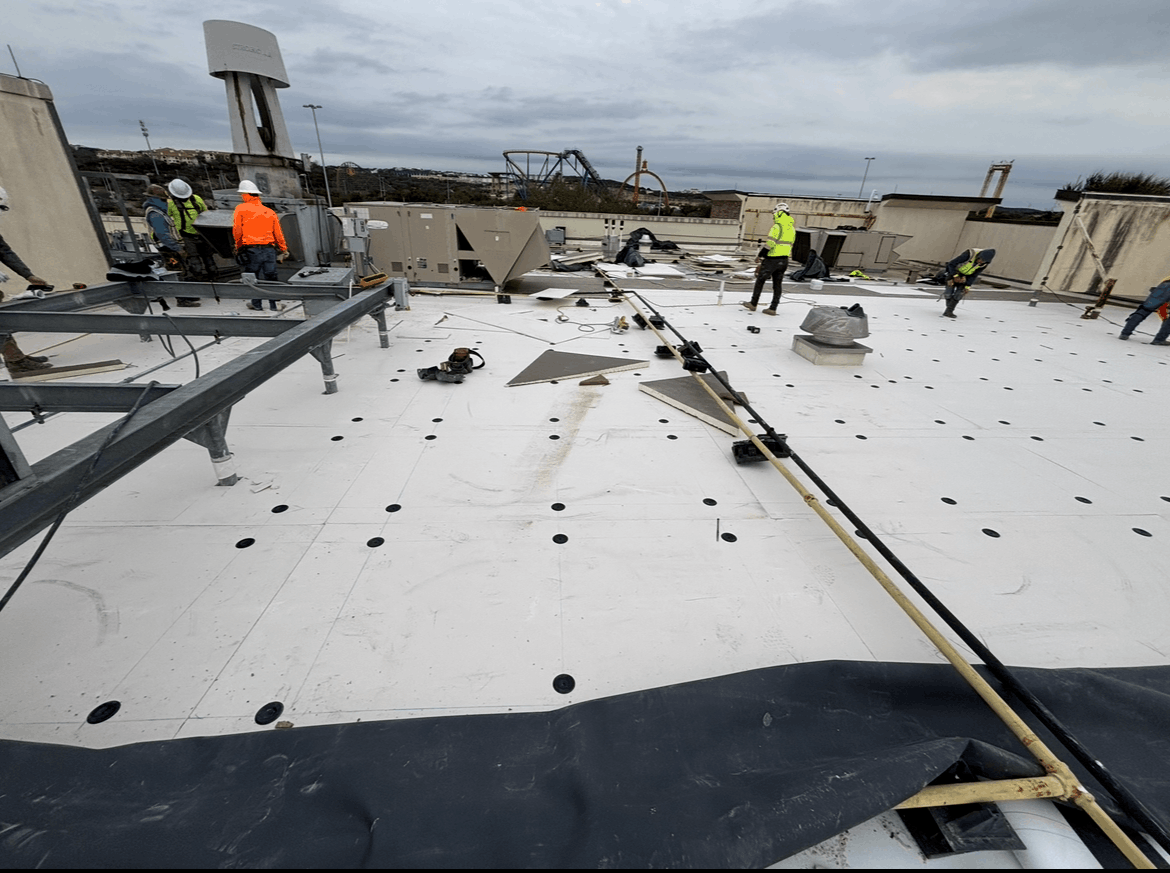 Damaged rooftop with workers assessing debris under an overcast sky