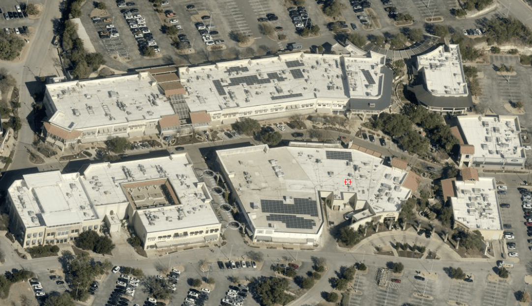 Aerial view of a large warehouse and retail complex with parking lots and surrounding roads