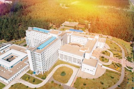 Aerial view of a large white multi-building campus surrounded by trees and pathways.