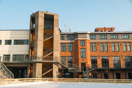 Brick building under renovation beside modern white and red-brick buildings on a sunny day