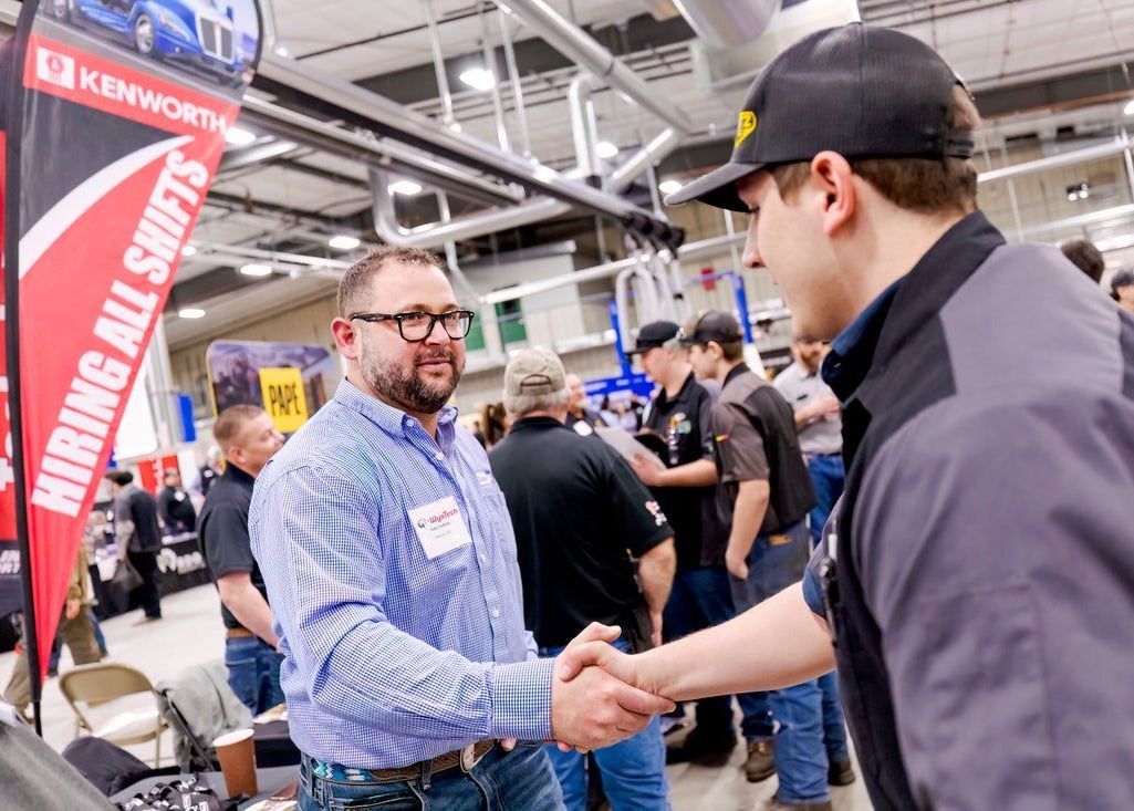 A man is shaking hands with another man at a job fair.