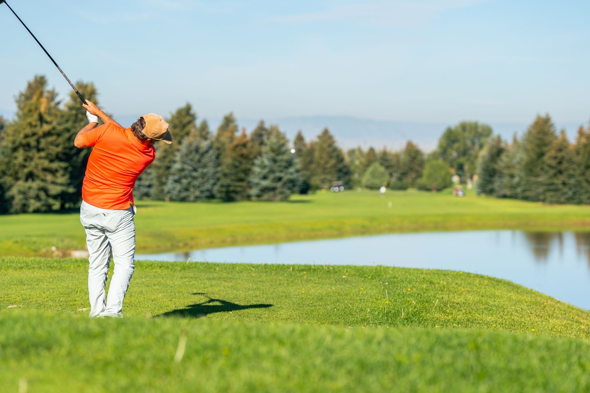 A man is swinging a golf club on a golf course.