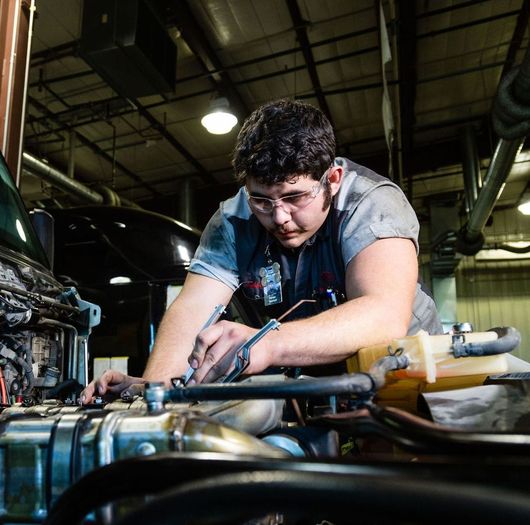 A man is working on a car engine in a garage