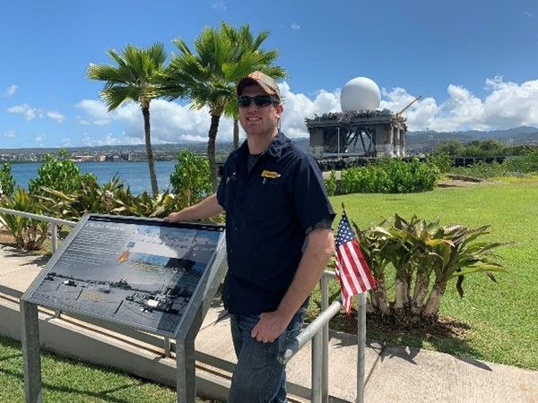 A man is standing in front of a sign with an american flag.