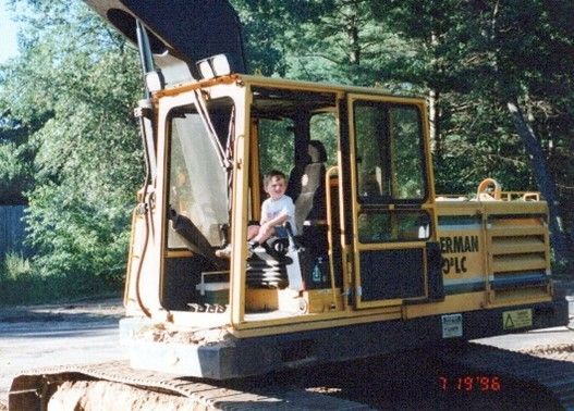 A little boy sits in the driver 's seat of a caterpillar excavator