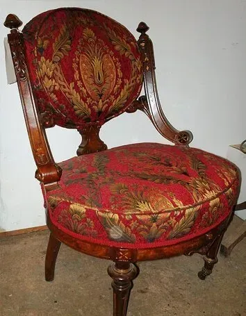 Restored antique chair with vibrant red patterned upholstery and polished wooden frame.