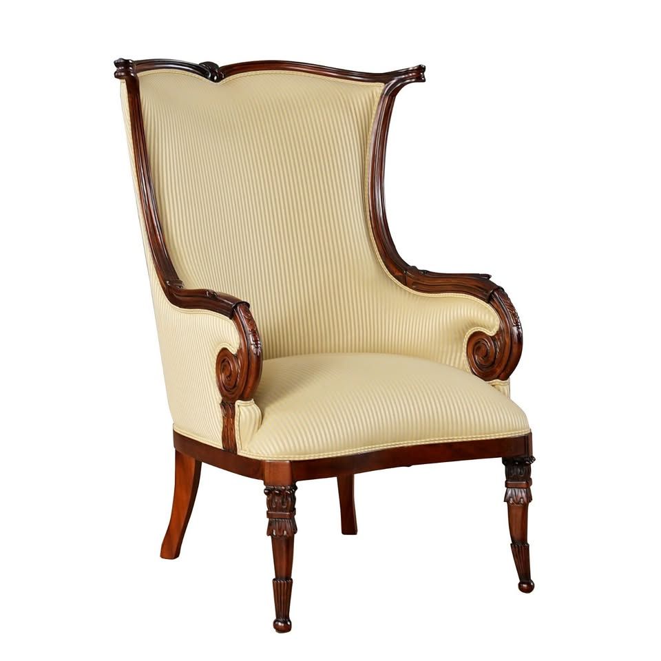 Elegant cream upholstered wingback armchair with carved dark wood frame and legs on white background