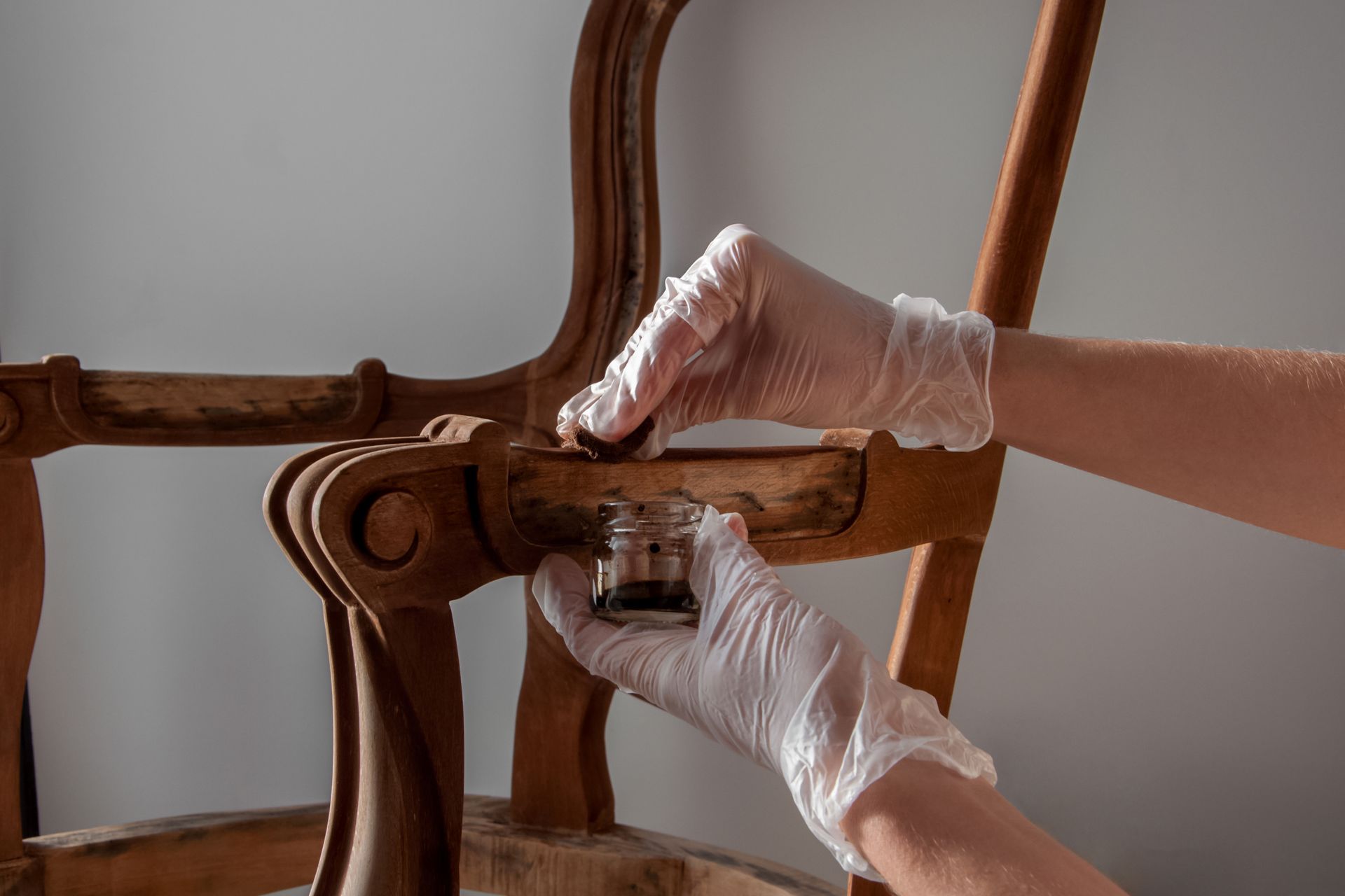 Professional applying finish to a vintage wooden chair frame for furniture restoration services. Professional applying finish to a vintage wooden chair frame for furniture restoration services.